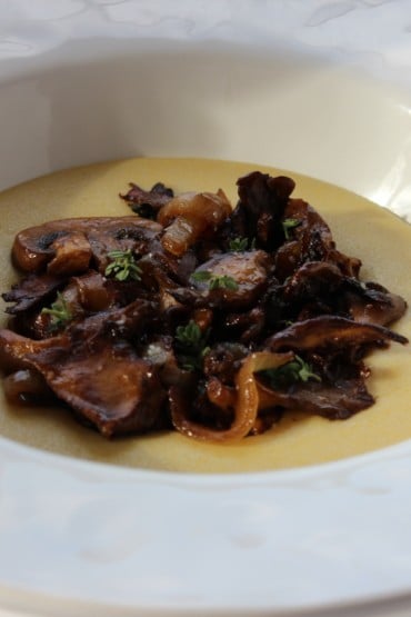 Polenta with sauteed mushrooms and caramelized onions in a white bowl