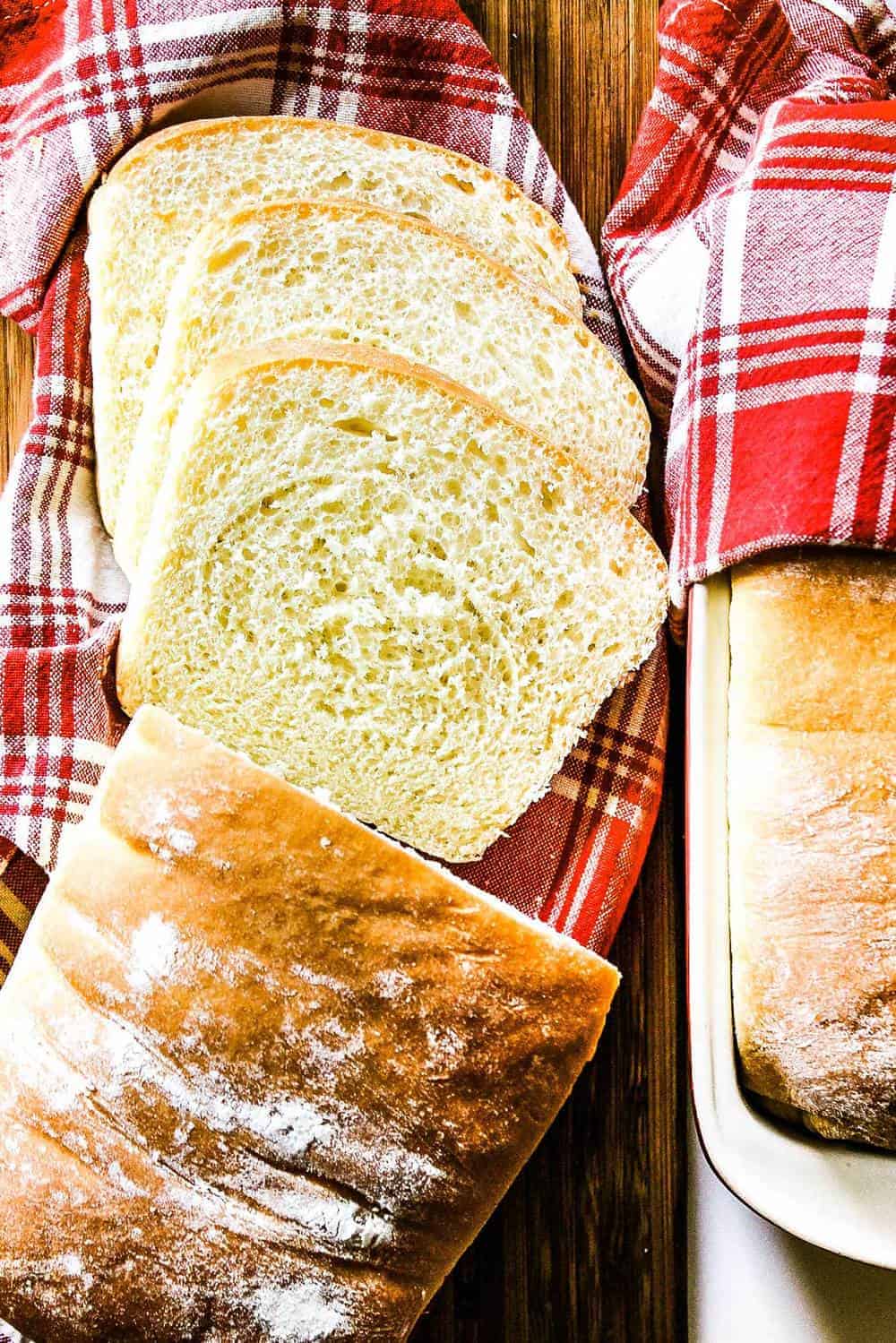 homemade white bread sliced and sitting on a red-checkered napkin. 