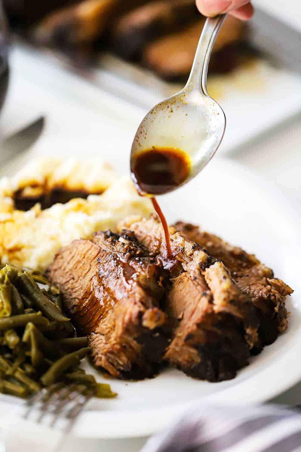 https://howtofeedaloon.com/wp-content/uploads/2014/02/sliced-brisket-on-a-plate-with-sauce-being-drizzled.jpg