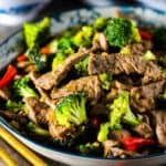 A blue bowl of beef and broccoli stir-fry.