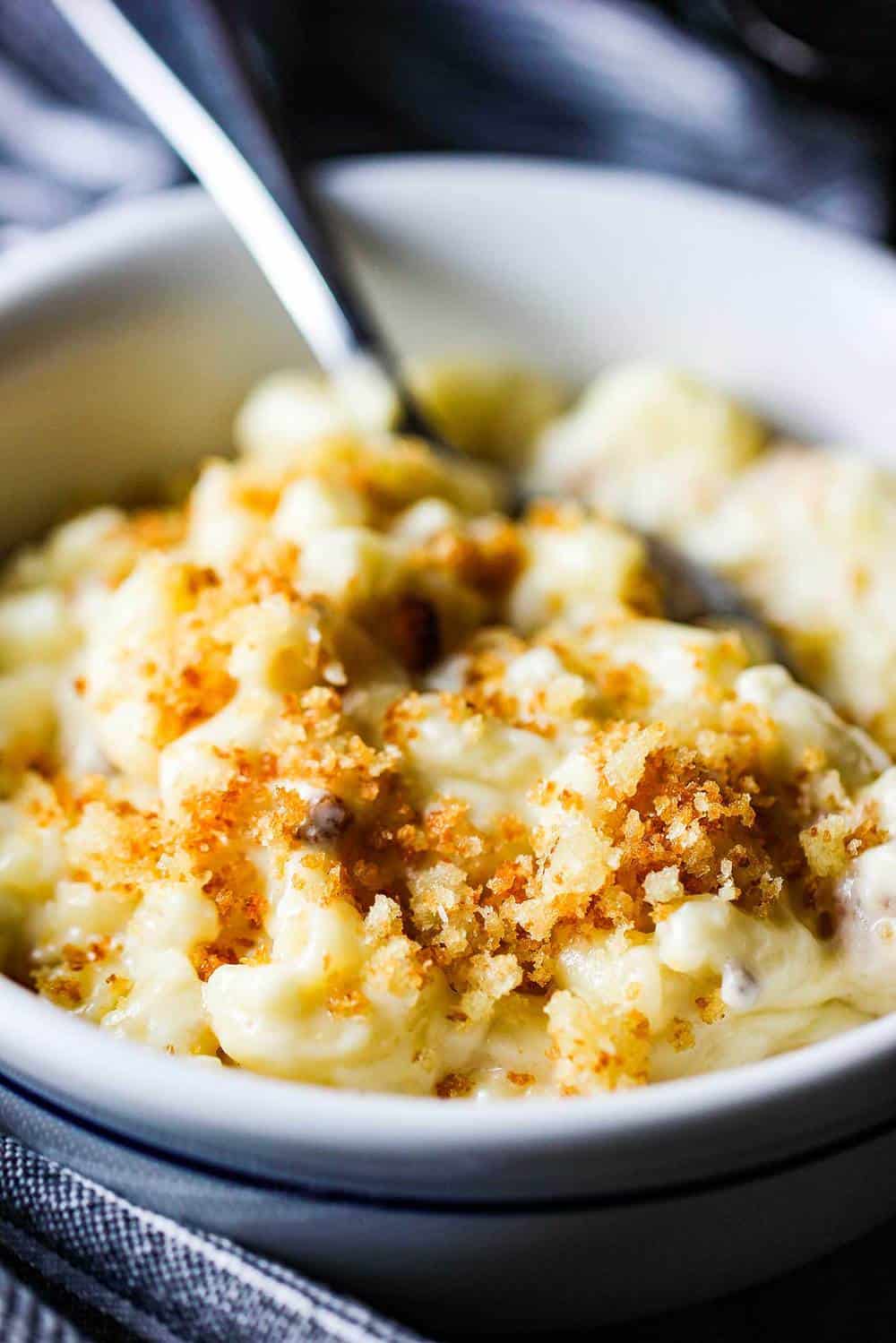 A bowl of the ultimate macaroni and cheese with a spoon in it. 