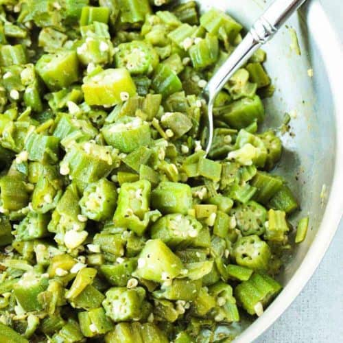 Skillet okra and garlic in a large skillet with a spoon