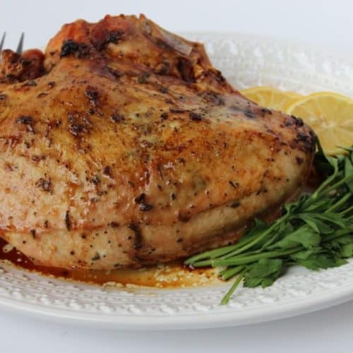 Whole roasted turkey on a white plate with a fork