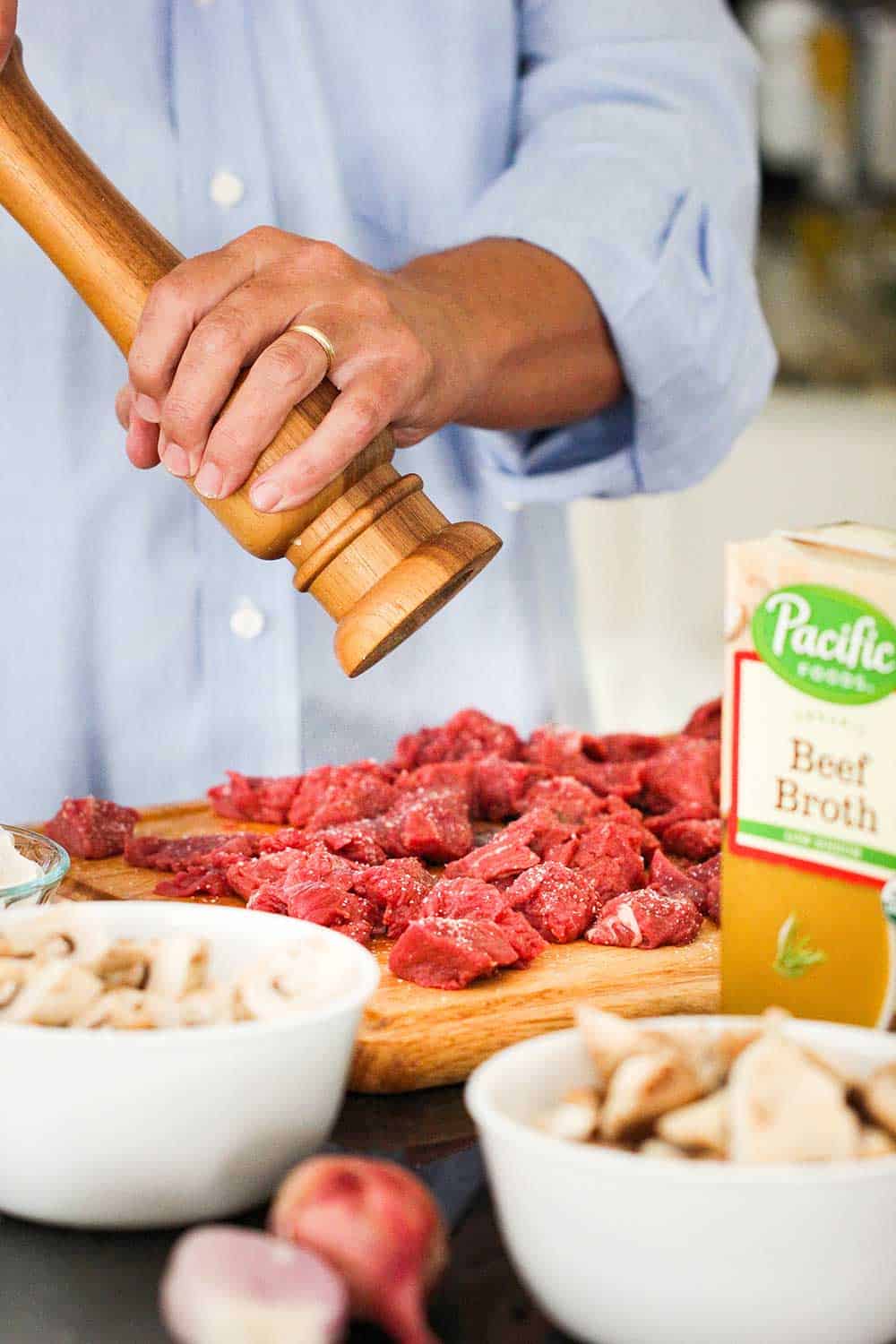 A pepper grinder being twisted over beef tenderloin for beef stroganoff