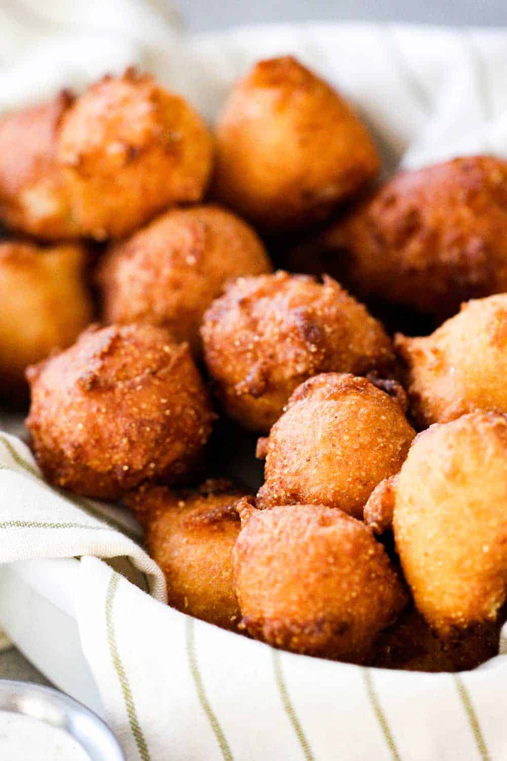 A close up view of a basket of homemade hush puppies. 