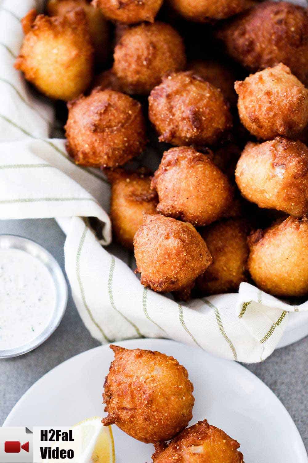 A basket of homemade Southern hush puppies next to a bowl of tartar sauce. 