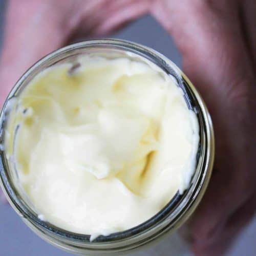 A hand holding a jar of homemade mayonnaise