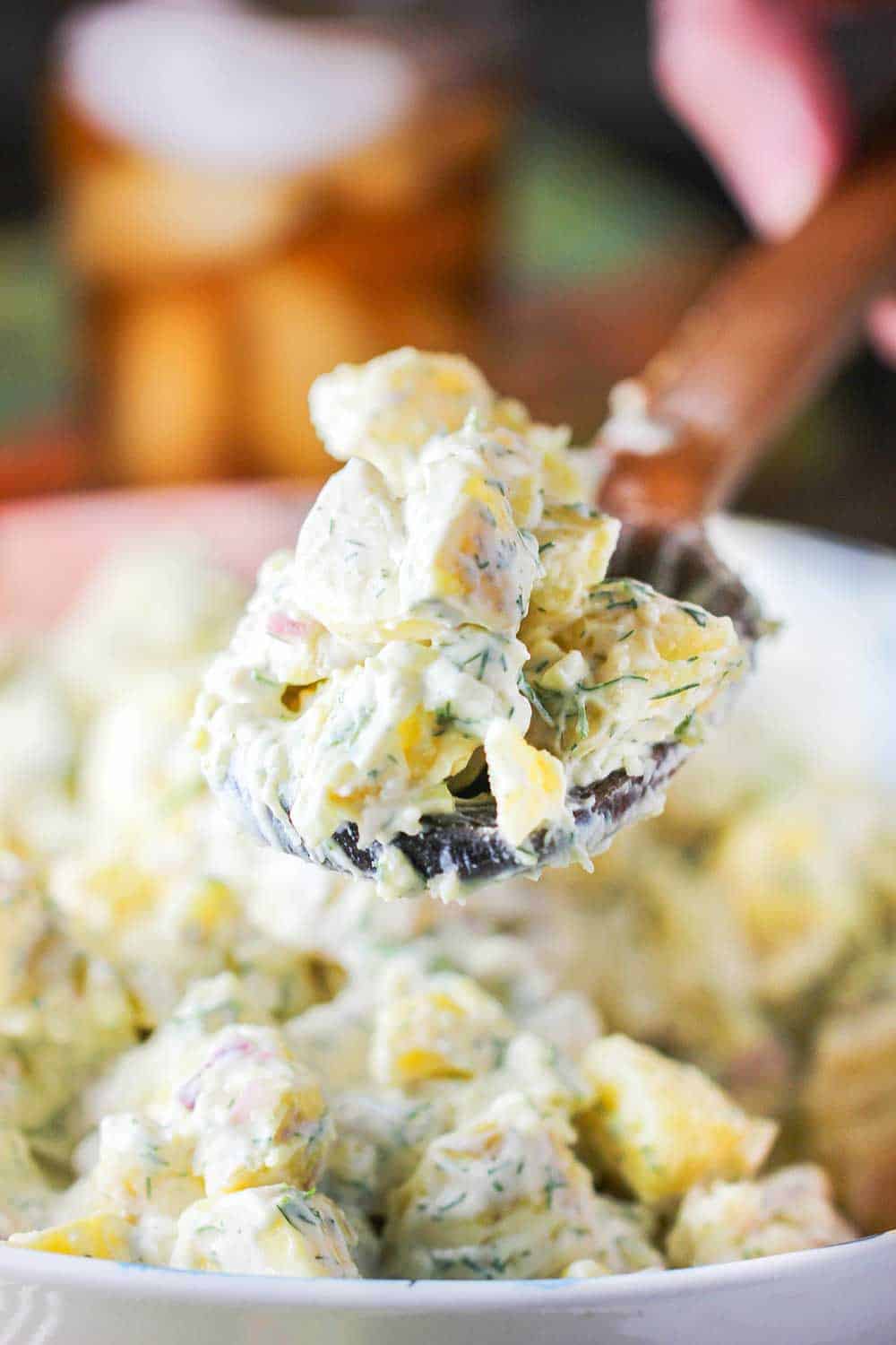A wooden spoon holding a pile of best-ever potato salad. 