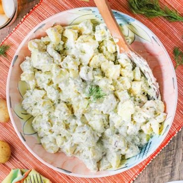 Best-ever potato salad in a large pink bowl with a wooden spoon.