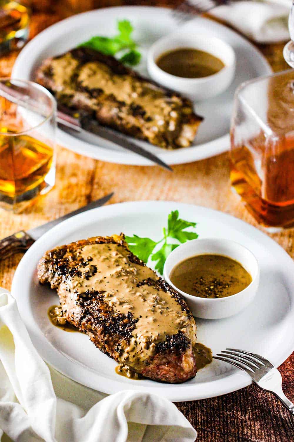 Serve the steak au poivre on a white plate with extra sauce on the side. 