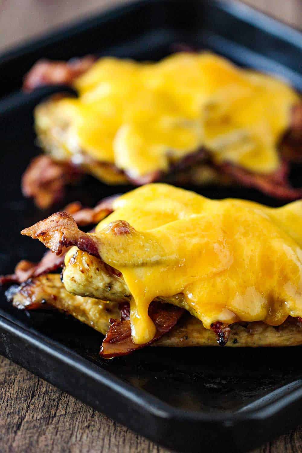 Two honey mustard chicken cutlets with bacon and melted cheese on top.