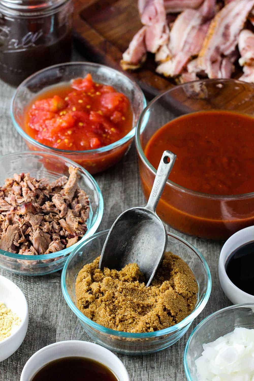 Bowls of ingredients ranging from tomatoes, BBQ sauce, brown sugar and brisket for baked beans. 