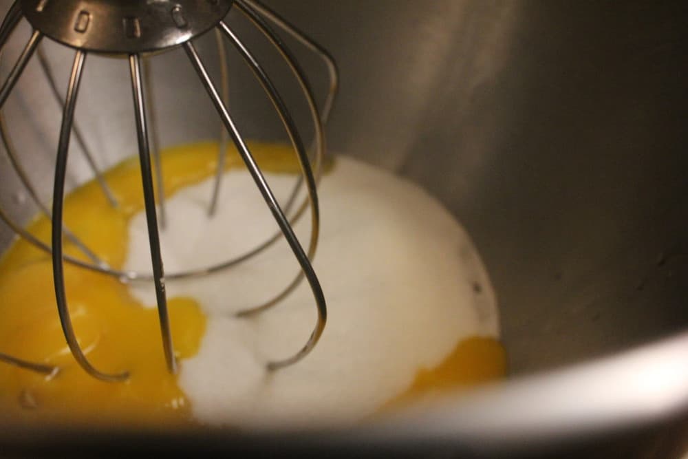 A whisk mixing together warm cream and eggs for creme brule.
