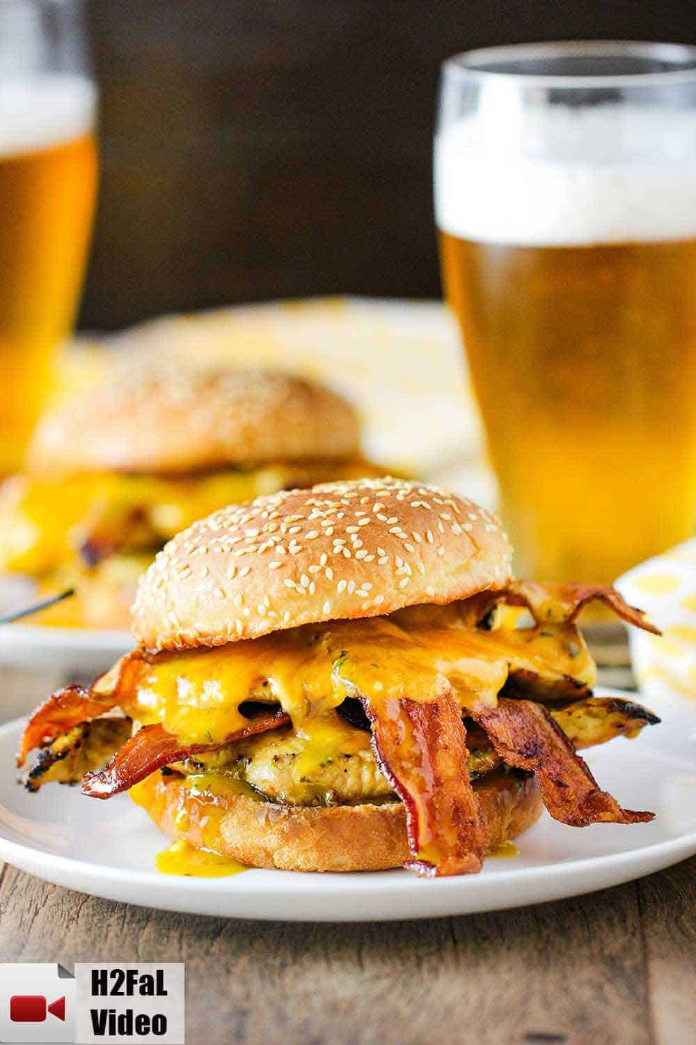 Honey mustard chicken sandwich on a white plate with a cold beer next to it. 