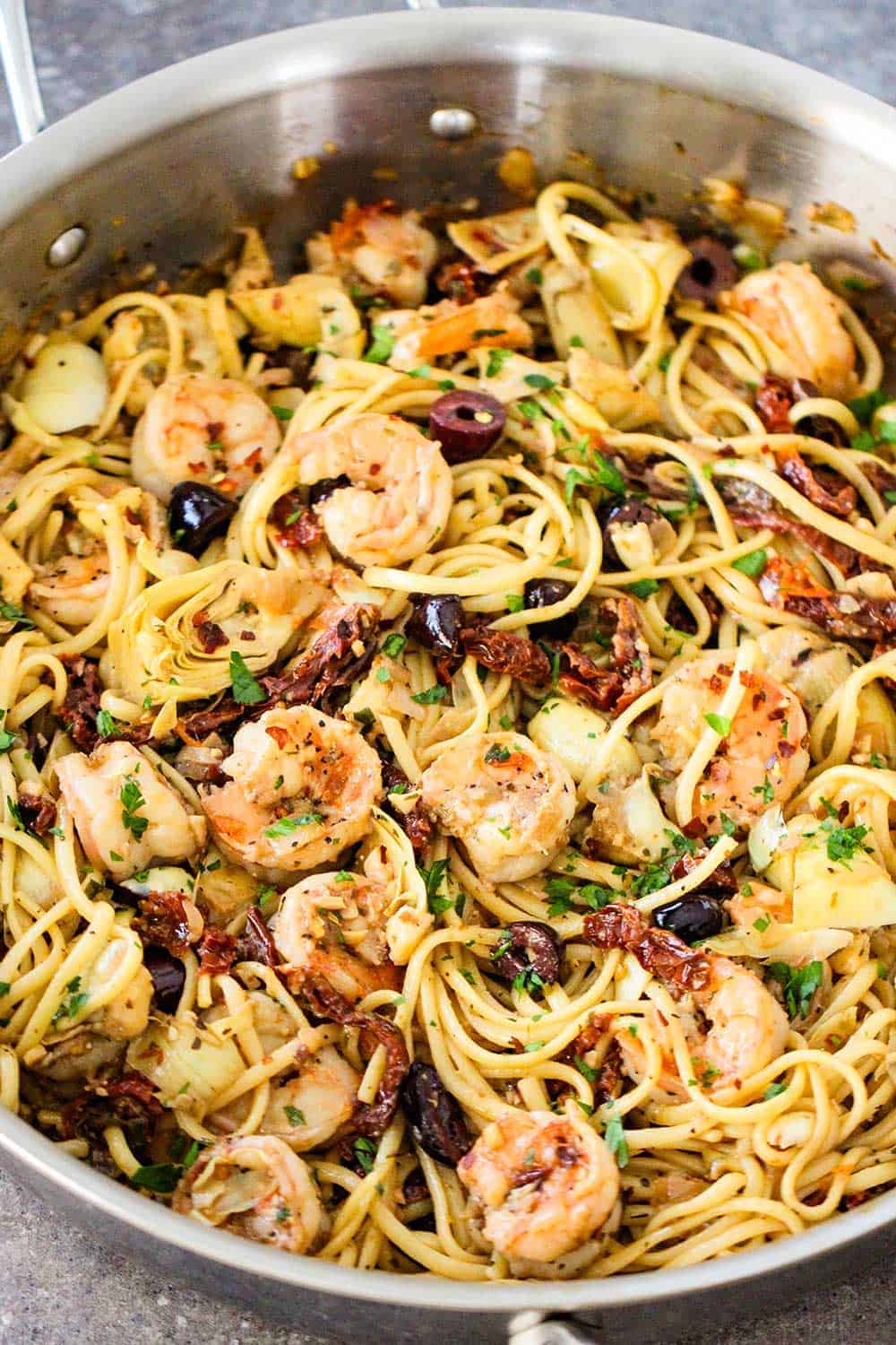 A large silver saucepan filled with Mediterranean pasta with shrimp. 