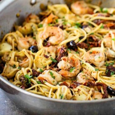 A large silver saucepan filled with Mediterranean pasta with shrimp.