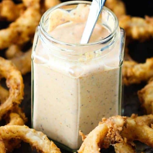 A jar of kickin' remoulade surrounded by onion rings