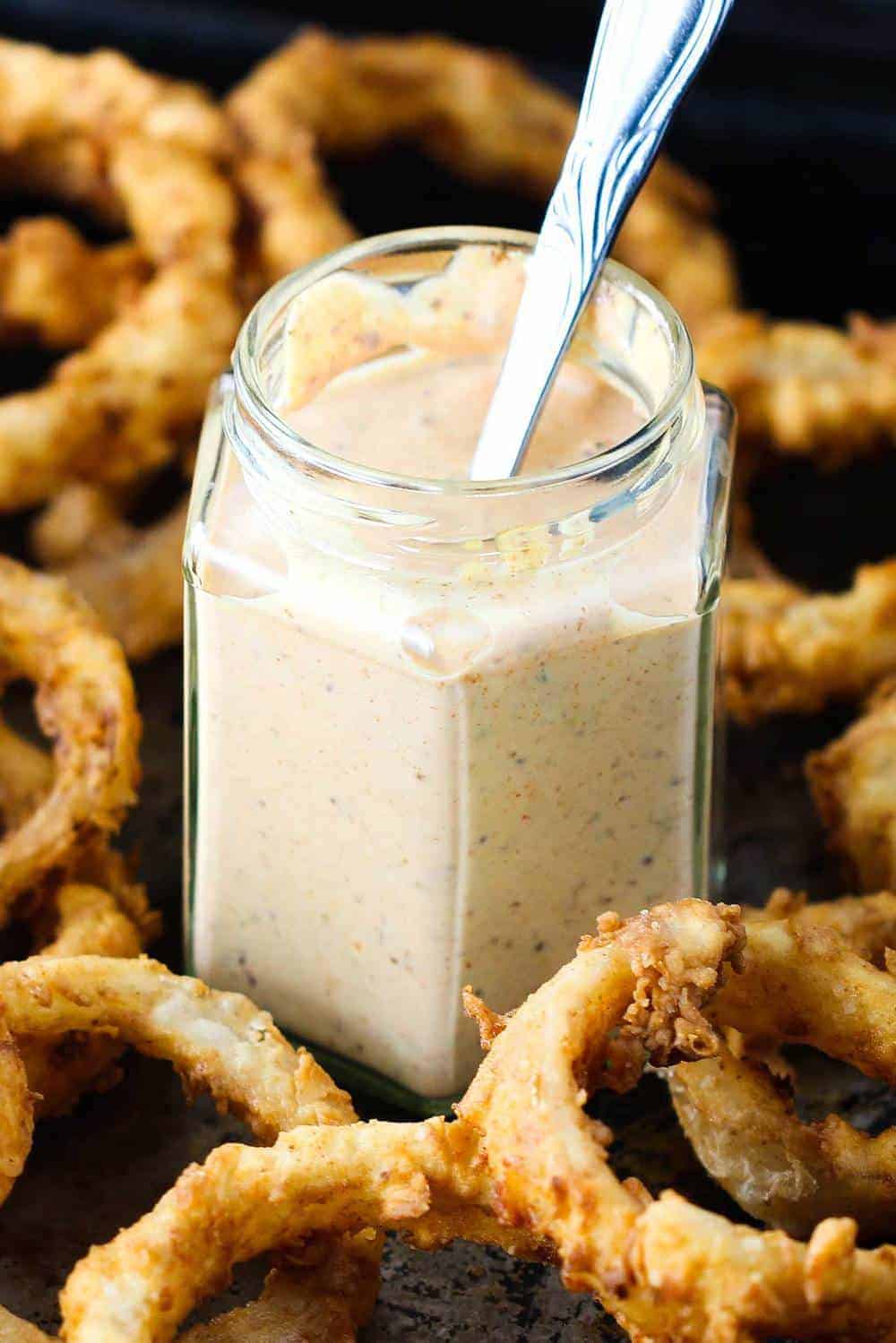 A jar of kickin' remoulade surrounded by onion rings
