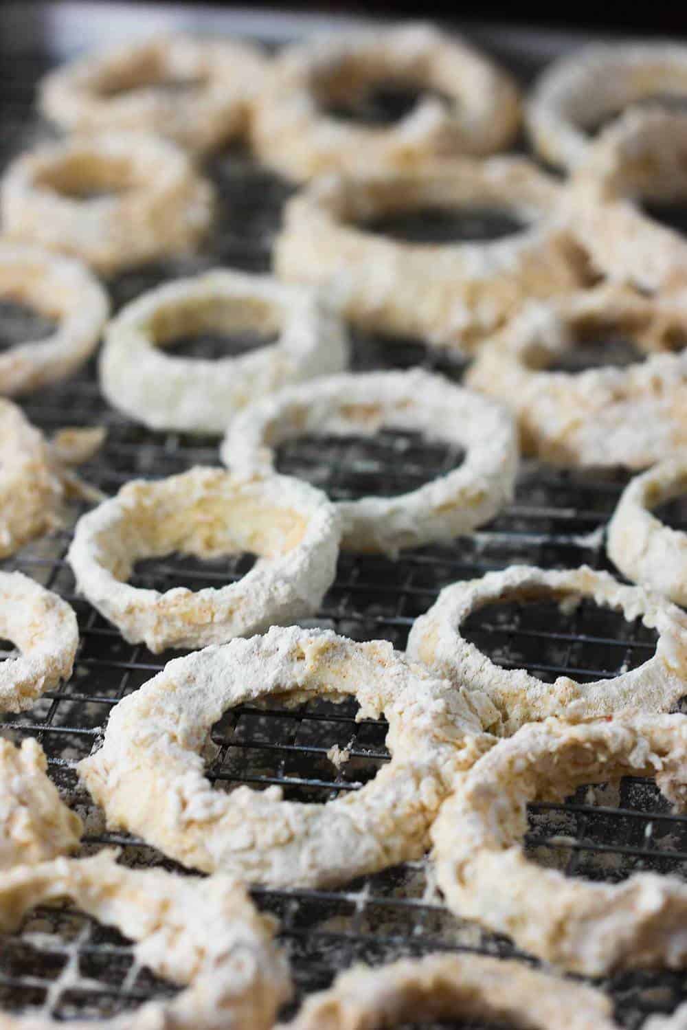 Breaded onion rings on a baking rack