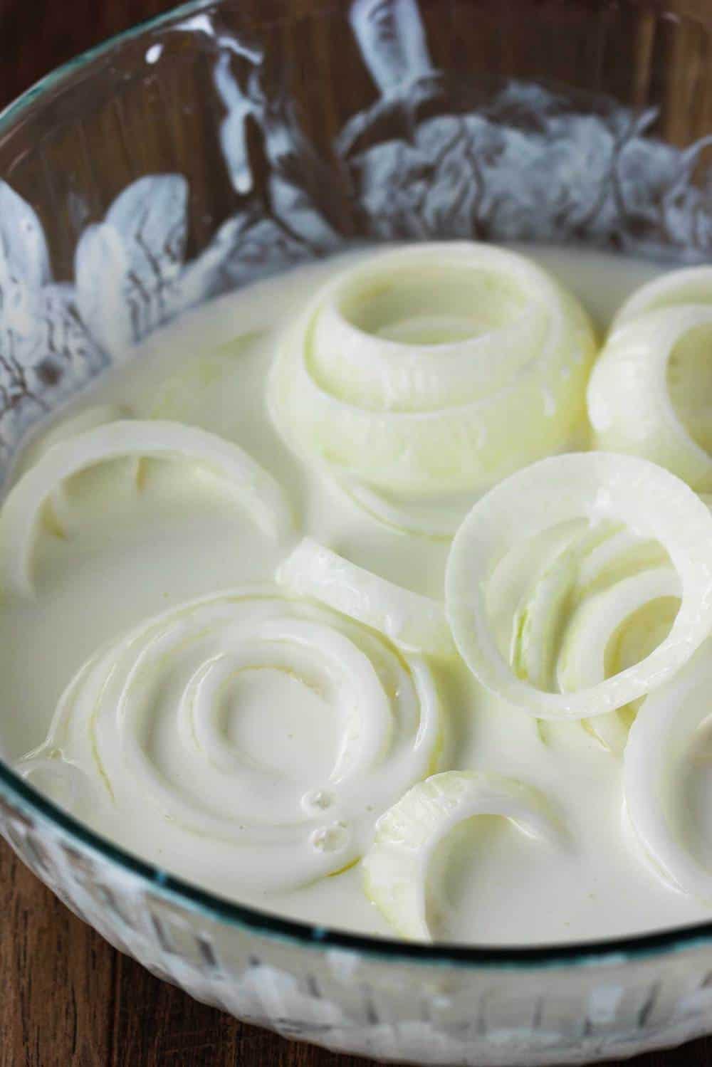 onion rings soaking in a bowl of buttermilk