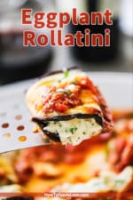 A spatula holding up a single eggplant rollatini with cheese oozing out the ends.