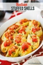An oval white baking dish filled with cooked Italian stuffed shells all sitting on a layer of marinara sauce.