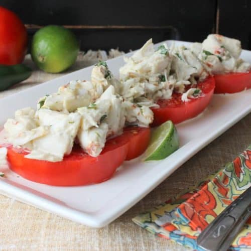 Lump Crab Tomato Salad on a white dish next to a patterned napkin with a fork