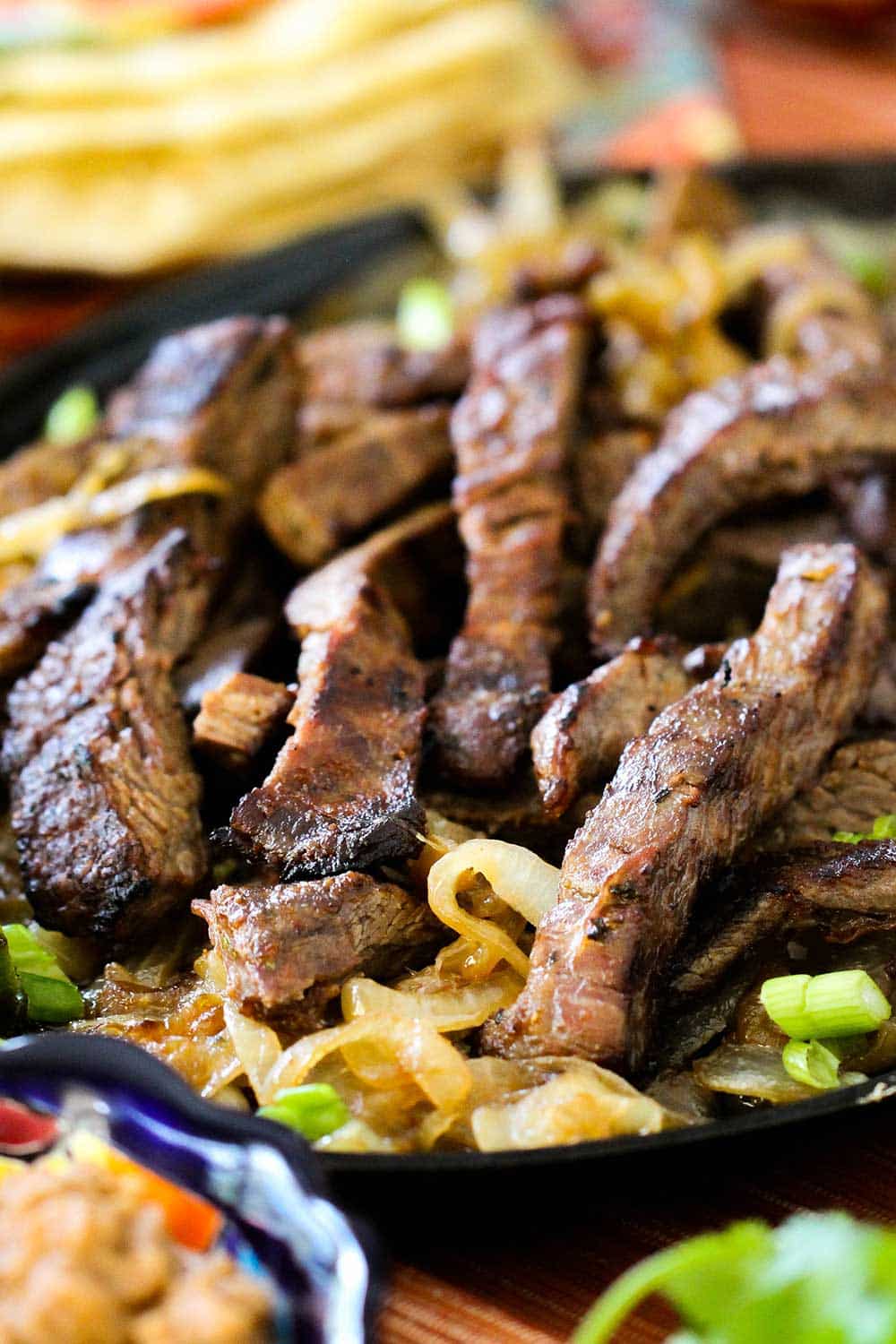 Steak fajitas on a bed of caramelized onions on a fajita pan. 