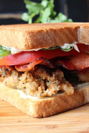 Fried Oyster BLT on a wooden cutting board
