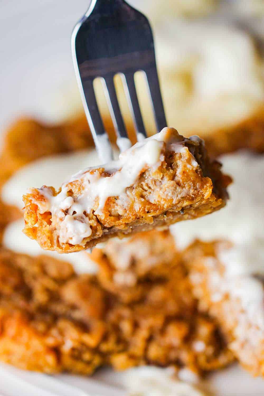 A fork holding a bite of Southern Chicken Fried Steak