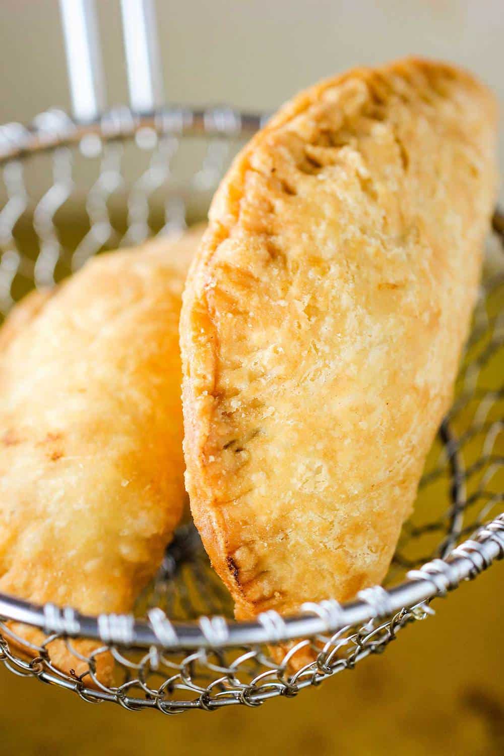 Two classic meat pies being pulled from hot oil 