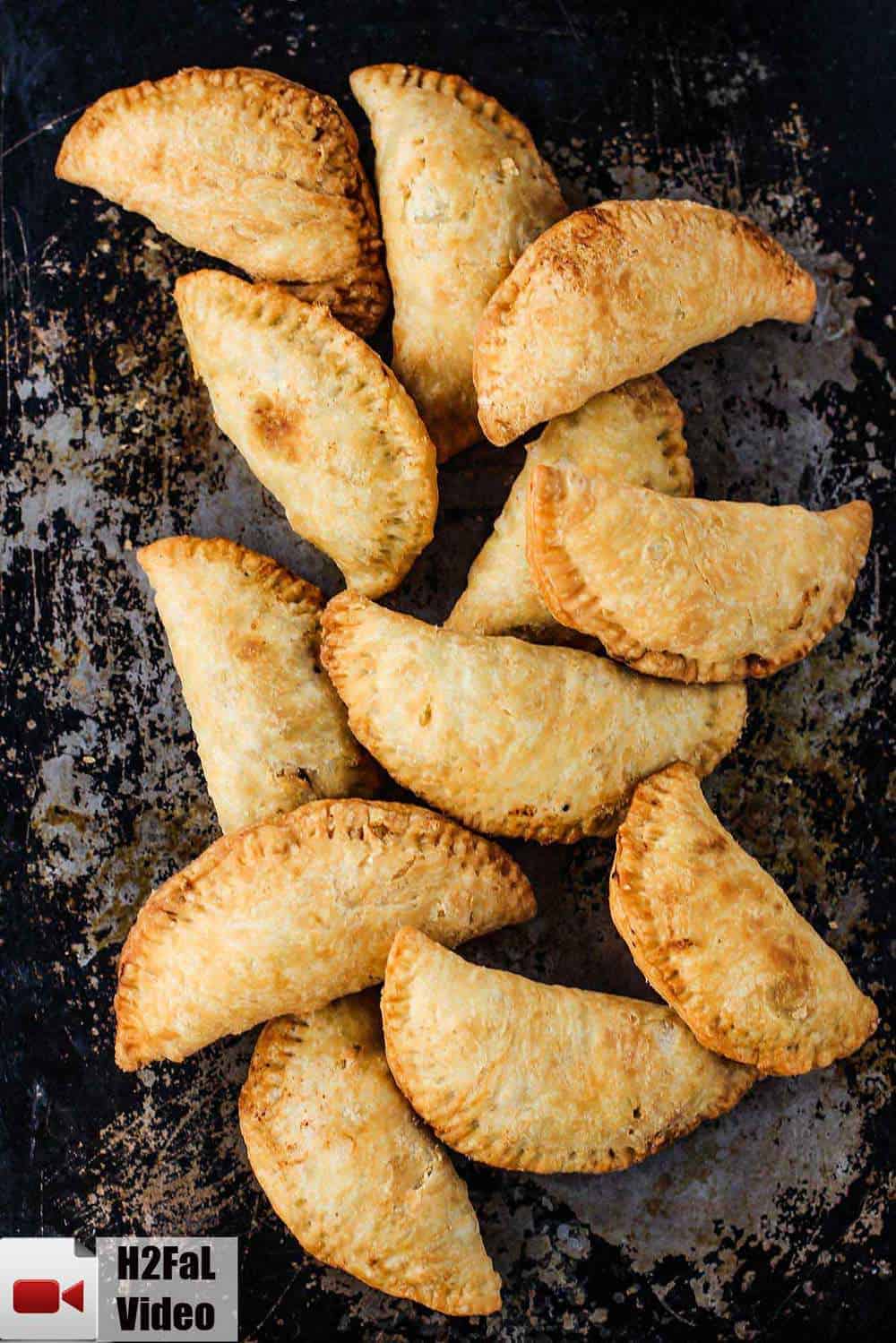 A dozen classic meat pies laying on a rustic baking sheet