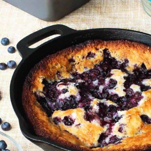 Lazy Day Blueberry Cobbler in a cast iron skillet next to blueberries