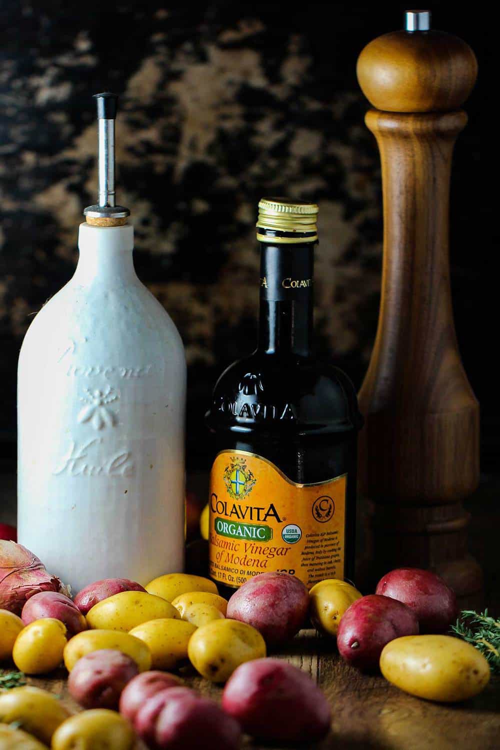 Potatoes, olive oil and balsamic vinegar on a cutting board.