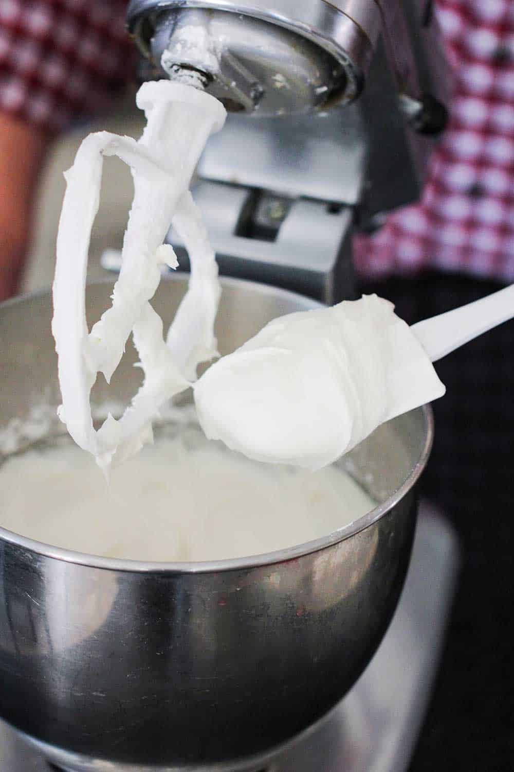 A spatula covered in cream cheese icing over a stand mixer. 