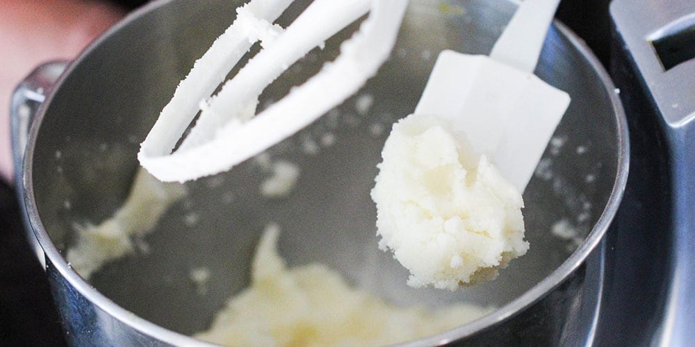 A spatula of creamed butter and sugar over a stand mixer. 