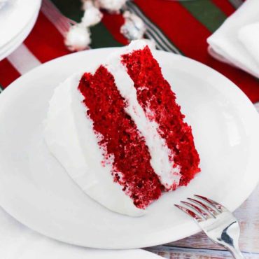 A large slice of red velvet cake on a white plate.