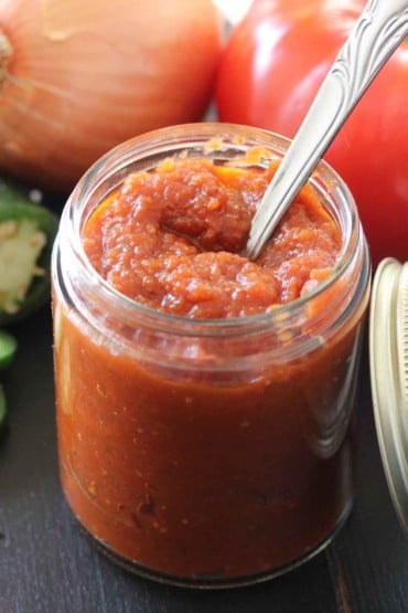 A jar of ranchero sauce with a silver spoon