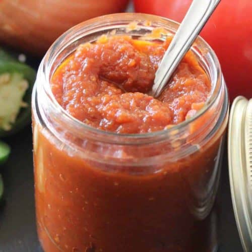A jar of ranchero sauce with a silver spoon