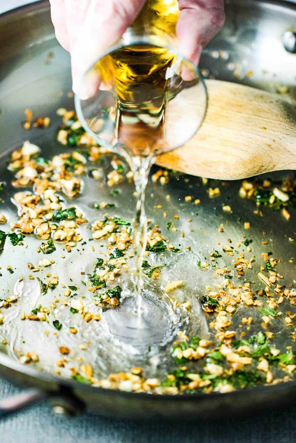 White wine pouring into a pan of sautéed white beans and sage