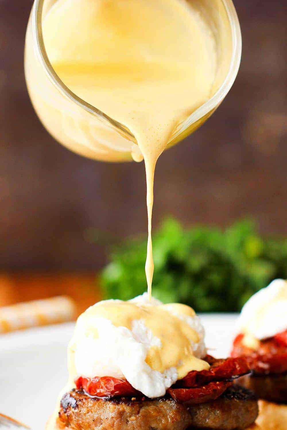Easy hollandaise sauce being poured onto eggs Benedict