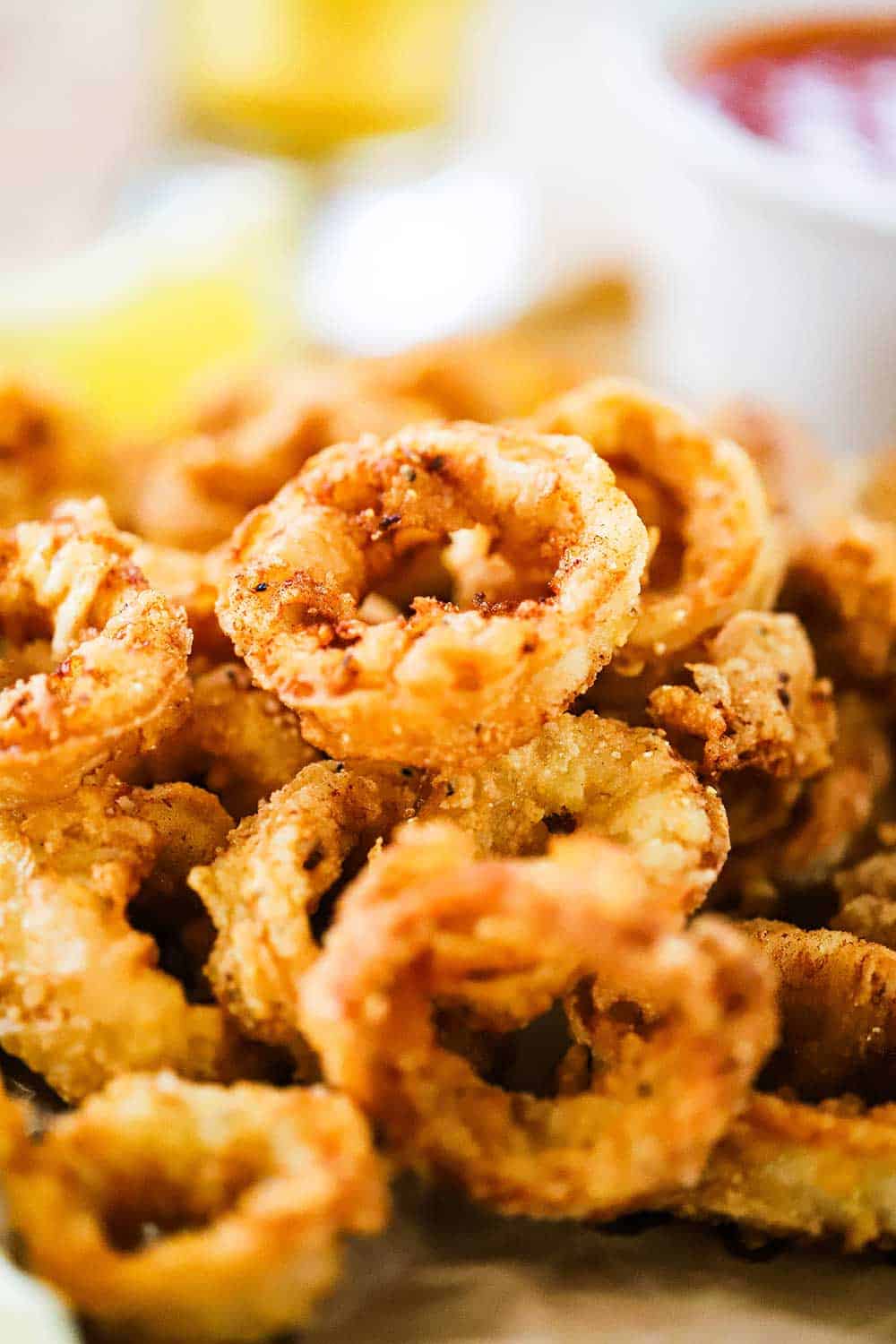 A pile of fried calamari sitting next to a small white bowl filled with marinara sauce. 