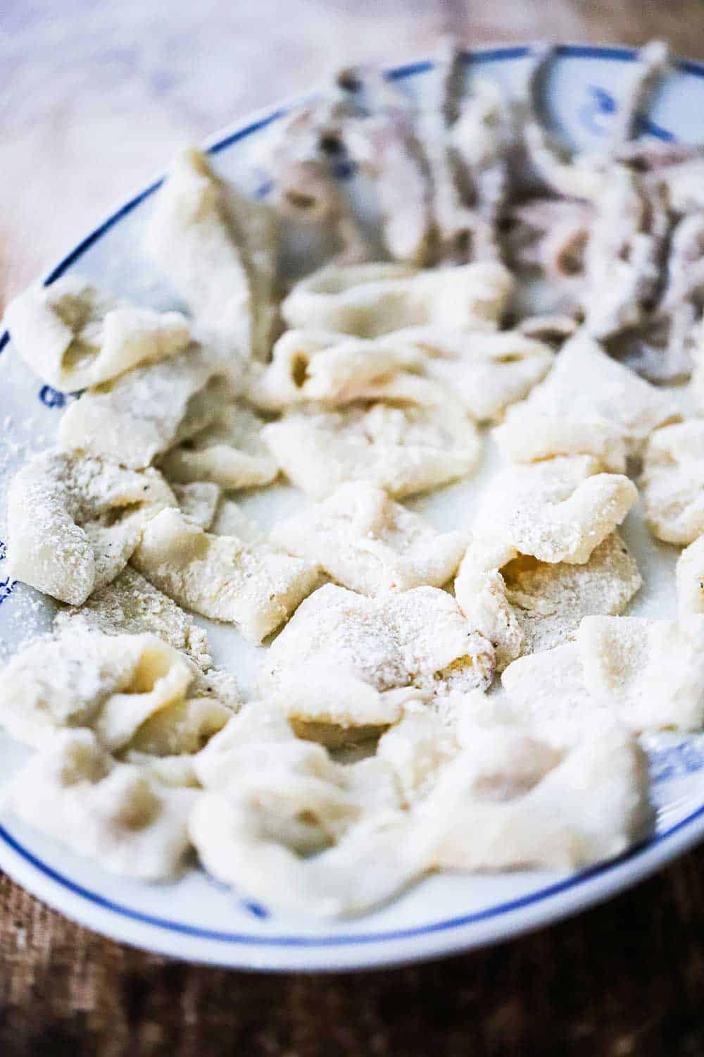 A large oval platter filled with floured calamari rings and tentacles before going into the deep fryer. 