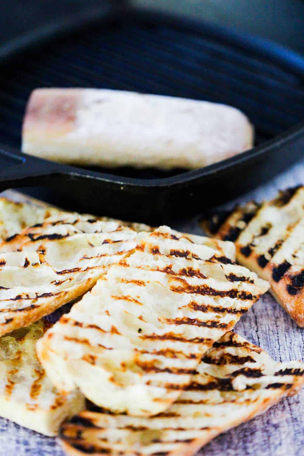 A stack of grilled bread next to a grill pan. 