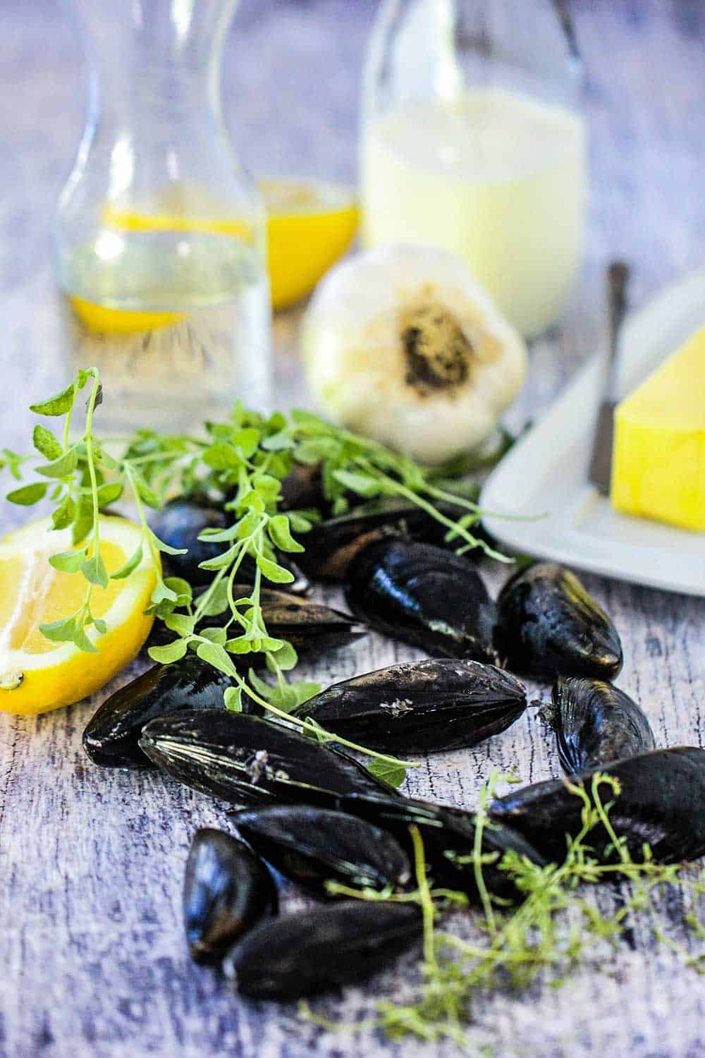 Fresh mussels, thyme, wine, garlic and cream on a white board. 