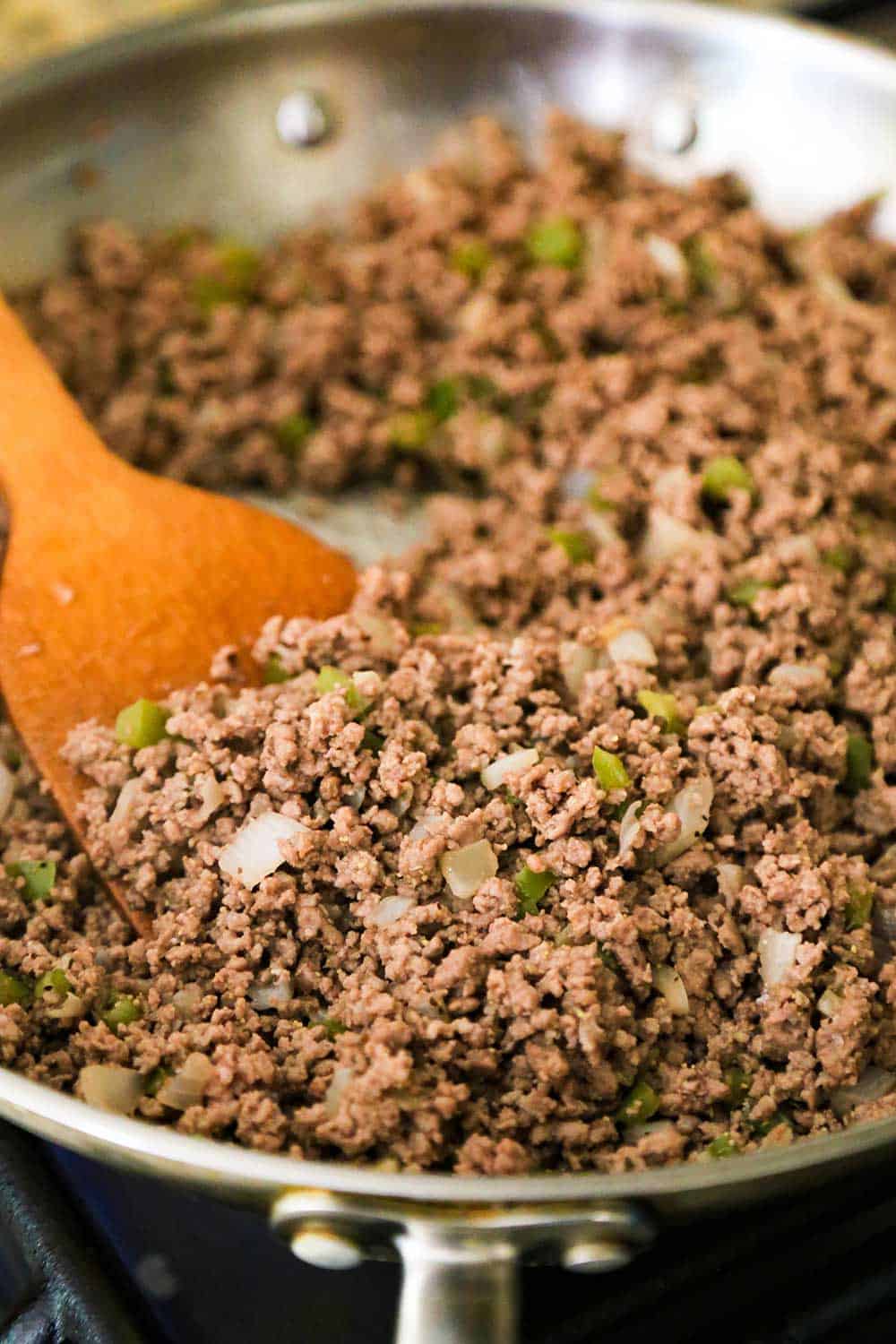 A large silver skillet filled with cooked ground beef for sloppy joes. 