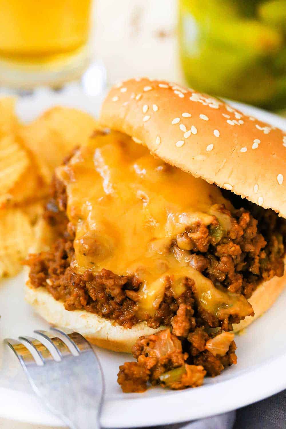 Slammin' Sloppy Joes sandwich on a white plate next to a jar of pickles. 