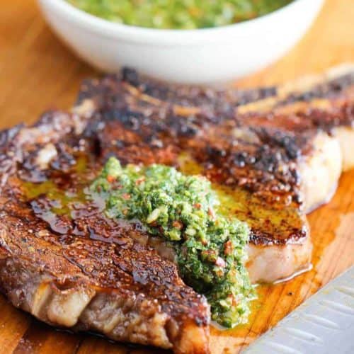 This is a grilled cowboy ribeye steak with chimichurri sauce on it