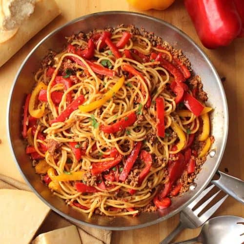 A large metal skillet filled with spaghetti with lamb ragu