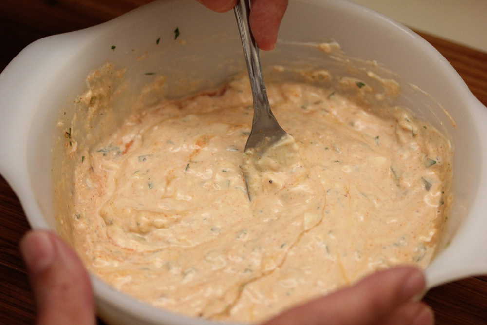 A fork mixing a white bowl filled with all the ingredients of Russian dressing. 